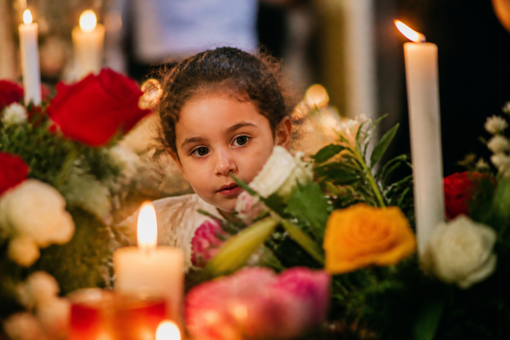 Petit enfant entre bougies et fleurs colorees