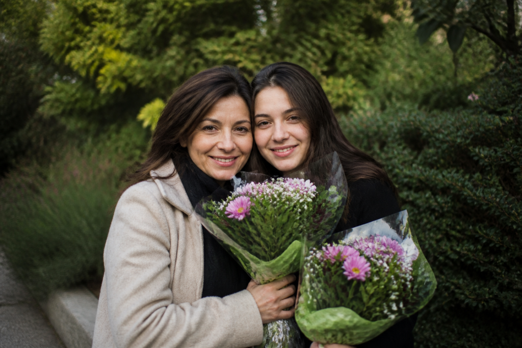 Mere et fille embrassees tenant des fleurs